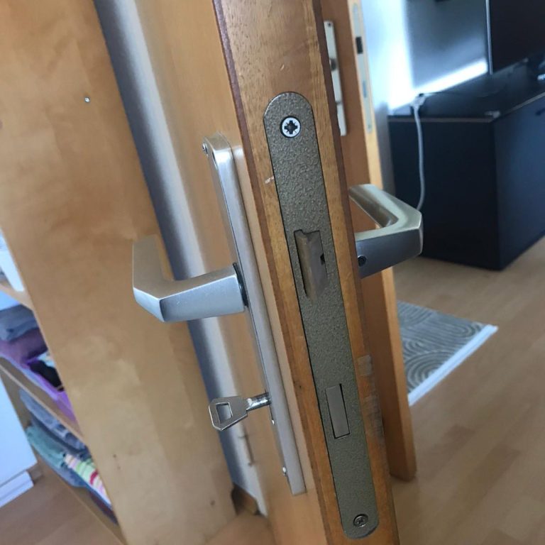 Holztür mit silbernem Türgriff und Sicherheitsschloss, beige Farbe.