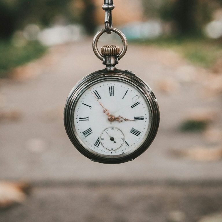 Schlüsseldienst Böblingen Silberne Taschenuhr mit römischen Ziffern, schwebend über einem Weg voller Blätter.