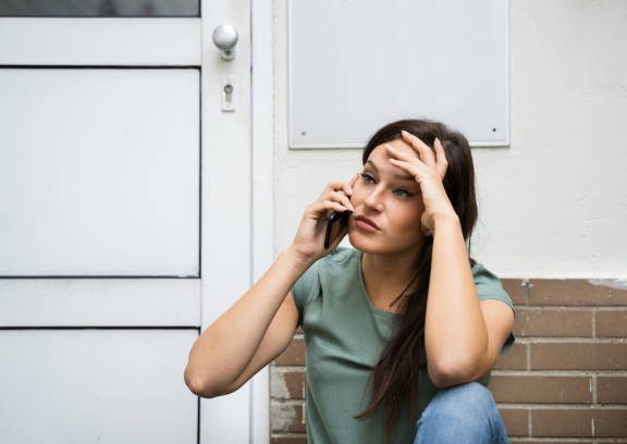 Frau mit besorgtem Gesichtsausdruck, die telefoniert und sich die Stirn reibt.
