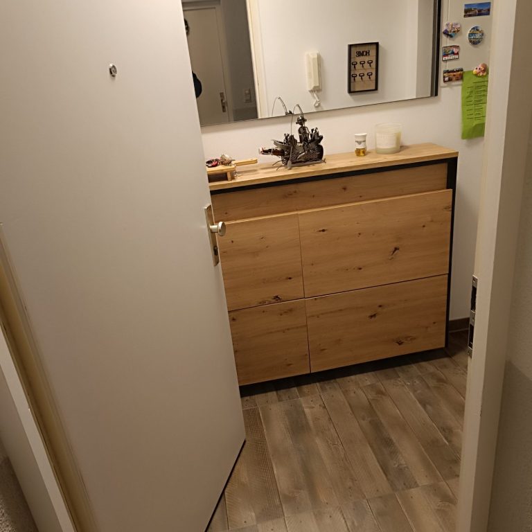 Schlüsselnotdienst Nordheim Ein Flur mit einer offenen Tür, einem Holzmöbel und einem Spiegel an der Wand.